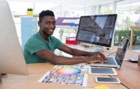 A man works on a computer with a monitor, representing the Adobe Lightroom Online Course.
