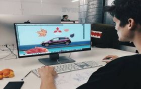 A man works on a computer displaying a car image, focused on his task, representing the Adobe XD Online Course.