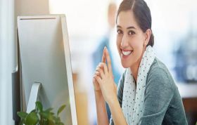 Smiling woman seated at a computer, representing the Agile Project Management course for enhancing project management skills and efficiency.