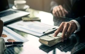 Man at a desk handing over money, representing Anti-Bribery Online Course and risks of heavy fines or long prison sentences.