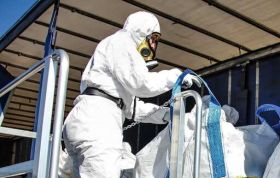 Man in protective gear loading a large bag, representing the Asbestos Awareness Course Online for safe handling and precautionary measures.