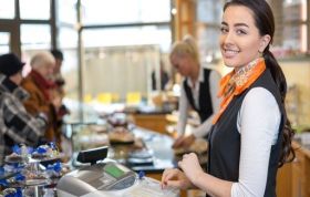 Saleswoman at checkout with another assisting customers, representing Underage Sales Prevention, focusing on unlawful sales of age-restricted products.