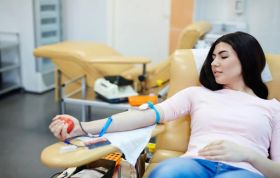 A woman calmly holds a blood bag in a medical setting, representing the Blood Transfusion Online Course.
