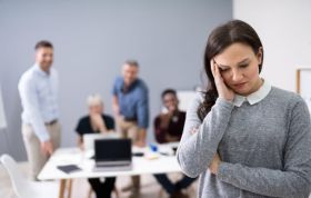 A woman looks stressed during a meeting, reflecting the impact of Bullying and Harassment in the Online Course.