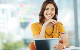 Smiling woman seated at desk with laptop, representing the Business Training Bundle course for developing key business and office skills.
