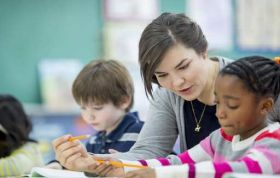 Teacher assisting students with homework, representing the CACHE Level 2 Award in Support Work in Schools and Colleges in a supportive setting.
