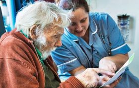Nurse and elderly man reviewing a document, representing the CACHE Level 3 Award in Awareness of Dementia course with focus and care.