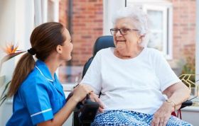 Nurse speaks with an elderly woman in a wheelchair, representing the CACHE Level 3 Award in Health and Social Care course.