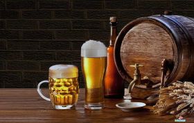 A glass of beer and wheat on a table with a wooden barrel, representing the Cellar to Glass Online Course.