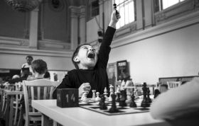 Young boy focused on a chess game in a bright, elegant room, representing the Chess Online Course with strategic learning.