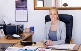 Woman seated at office desk with computer and documents, representing the Cisco CCENT Course with Practice Lab for foundational networking skills.