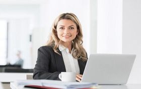 Smiling woman in business suit working on laptop, representing the Cisco CCNP Switch course for advanced networking and switch configuration.