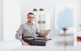 Man wearing glasses sitting at a desk, focused on a tablet, representing the Cloud Computing Security Knowledge course.