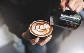 Man preparing espresso at a coffee machine, representing Coffee Skills and learning to make quality espresso-based drinks.