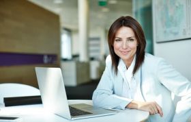 Confident woman seated at desk with laptop, representing the Complete Cisco Networking Bundle with Practice Labs for hands-on IT training.