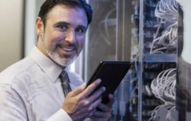 Man in tie holding tablet, focused on device, representing the Complete Cisco Networking Bundle course for comprehensive network training.