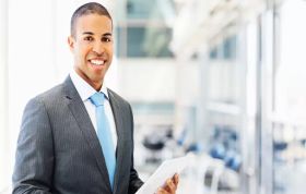 Suited man holding tablet and focused on screen, representing the Complete Microsoft Training Bundle for professional software skills development.