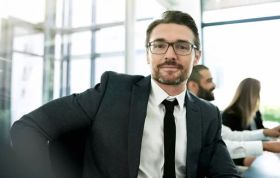 A man in a suit sits at a desk, focused on his work, representing the Complete Project Management Bundle course.