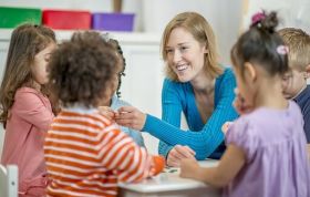 A woman instructs children in a classroom, representing the Compliance Training for Childcare Professionals course.