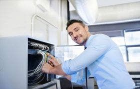 Man working on a server rack in a well-lit room with tools, representing the CompTIA A+ Course for IT support and hardware skills.