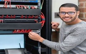 Man inspecting server rack in a data center, representing the CompTIA Network+ Course with focus on networking and infrastructure skills.