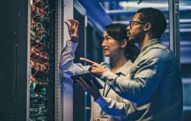 Two individuals inspecting a server rack in a data center, representing the CompTIA Network+ N10-009 Course.