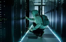 A person in a hoodie works with servers in a server room, representing the CompTIA PenTest+ course.