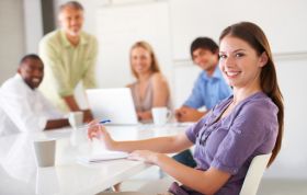 Woman at a table engaged in discussion with group, representing the Configuring Windows 8 Online Course for system setup and management skills.
