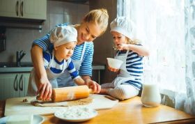 Mother and children happily making dough together, representing Cooking with Children Online course at home.