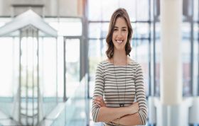 Smiling woman in a modern office, representing the Developing Microsoft Azure and Web Services Online course in a positive work environment.