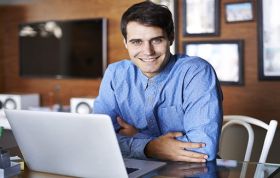 Smiling employee at laptop, representing Developing Microsoft SQL Server 2012 Online Course for database professionals.