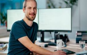 Man seated at desk working on two monitors representing Developing Solutions for Microsoft Azure AZ-203 Online course.
