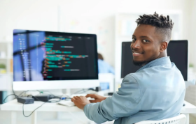 A man sits at a desk, focused on a computer screen, representing the DevOps Fundamentals Online Course.