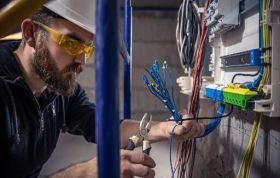 Electrician handling cables to fix an issue, representing Electrical Safety Online Course and risks like electric shock or burns at work.