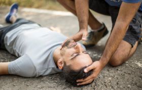 Man lying on the ground with head on the surface, illustrating a seizure episode for the Epilepsy Awareness Online course.