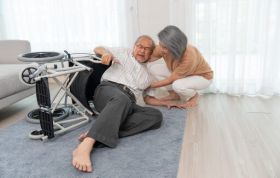 Senior woman assists elderly man in wheelchair, symbolizing support and care for the Falls Prevention Online course.