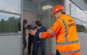 A man in an orange safety vest talks with a woman, representing the Fire Warden (Fire Marshal) Online course.