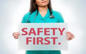 A woman in scrubs holds a "Safety First" sign, emphasizing safety in healthcare, representing the Health & Safety in Healthcare Online course.