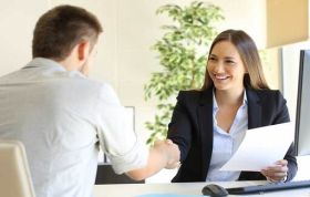 Man and woman shake hands over a desk, symbolizing collaboration for the Interview Skills Online course.
