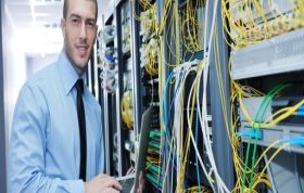 Man in tie holding laptop in front of server rack, representing the IT Professional Networking Bundle course for advanced network skills