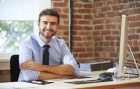 Man in shirt and tie working at desk with notepad, representing ITIL® 4 Foundation Online course focus and learning.
