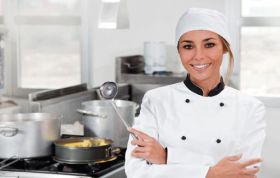 Female chef holding spoon in kitchen, representing Level 1 Food Safety course, focused on food hygiene and safe kitchen practices.