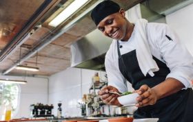 Chef prepares ingredients in a modern kitchen, representing the Level 2 Food Safety and Hygiene Online course with focus on cleanliness.