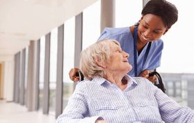 Nurse assists elderly woman in a wheelchair, representing the Level 2 Person Centred Care Online course focused on compassionate healthcare.