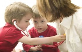 Three children, two boys and a girl, playing with doctor tools, representing Paediatric First Aid for those working with children and infants.