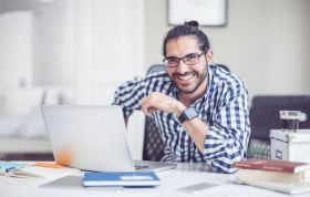 Confident man at desk in front of laptop, representing the Linux and UNIX Certification Bundle course for essential system administration skills.