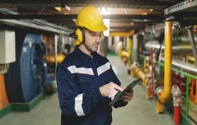 Man in factory uniform holding tablet, representing Lone Working Essentials and staying safe during day to day work activities.