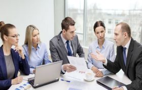 Man explaining data to colleagues at office desk, showcasing Managing Change techniques to handle change in the workplace effectively.