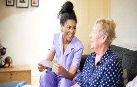 Nurse helps elderly woman with medication, representing the Managing Risk and Minimising Restraint Online course for safer care practices.
