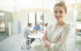 A woman smiles in an office, exuding positivity, representing the Mastering Your iPhone and Android Phone Bundle course.